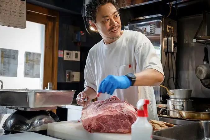 肉を調理する男性スタッフ